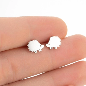 Close-up of small hedgehog stud earrings in silver stainless steel on a fingertip