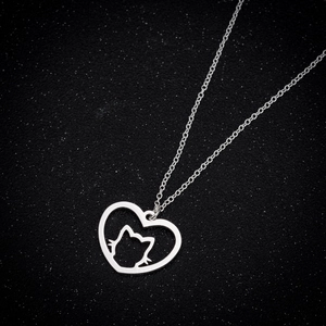 Vue macro d'un pendentif chat argenté dans un cœur sur un fond noir texturé élégant
