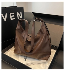 Detail of a dark brown pebble leather hobo bag presented in a luxury gift box