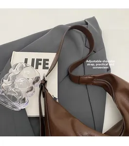 Detail view of adjustable strap and polished brown leather on a minimalist hobo bag