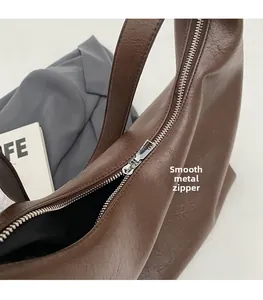 Detail of a smooth silver metal zipper on a dark brown lychee leather shoulder bag
