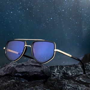 Polarized black and gold metal pilot sunglasses for men on a rugged dark stone surface