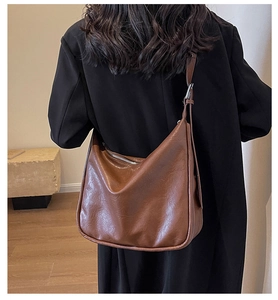Detail of a large brown vintage hobo bag worn with a black coat for daily commute fashion
