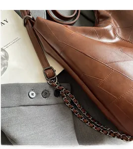 Detailed close-up of brown vintage tote bag featuring geometric patchwork stitching and chain strap