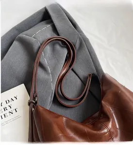 Close-up of brown crocodile pattern tote with vintage bronze hardware and quilted stitching