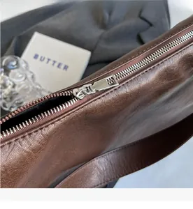 Detail of the smooth silver metal zipper on the large brown vintage leather tote bag