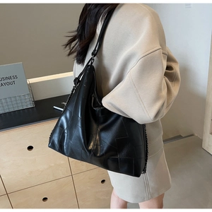 Detail of black geometric patchwork shoulder bag with leather strap and chain link detail