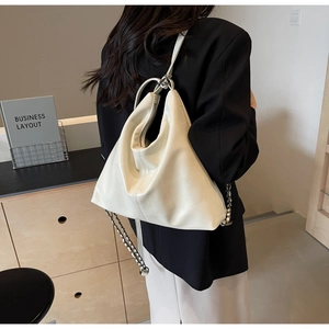 Detail of off-white faux leather shoulder bag with geometric stitching and chain strap