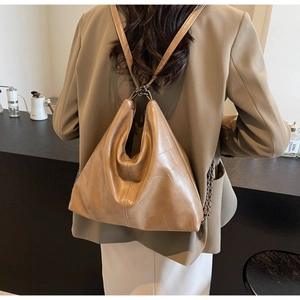 Detail view of a vintage light brown leather backpack with geometric stitching on model