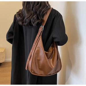 Detail view of large brown retro hobo bag with wide adjustable strap and smooth leather texture