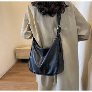 Detail of a large black vintage hobo bag with adjustable eyelet strap on a model