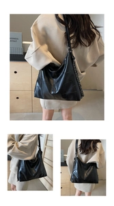Detail of black faux crocodile skin tote with geometric stitching and metal chain