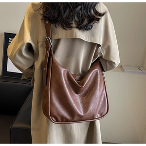 Detail of the soft brown leather texture and wide adjustable shoulder strap on the tote