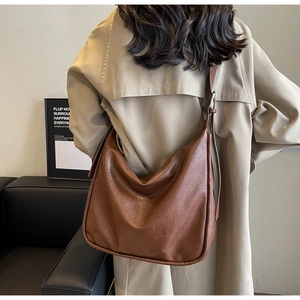Close-up of brown large-capacity tote bag with adjustable wide strap on woman shoulder