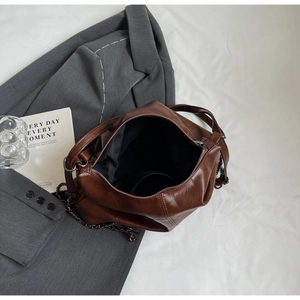 Detail of deep brown wax leather texture and spacious interior with silver chain strap