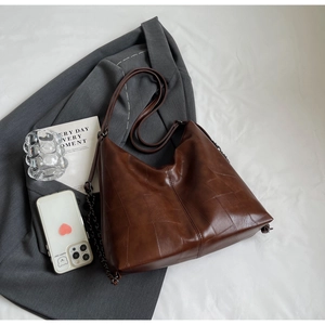 Detail of coffee brown faux leather tote with textured patchwork and metal chain strap
