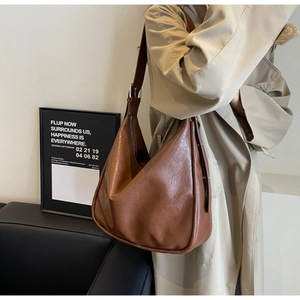 Detail of a large brown faux leather hobo bag with pleated texture and wide strap