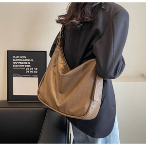 Detailed view of caramel brown leather bucket bag on shoulder showing soft texture