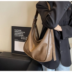 Brown large-capacity Hobo shoulder bag with adjustable strap worn by a model