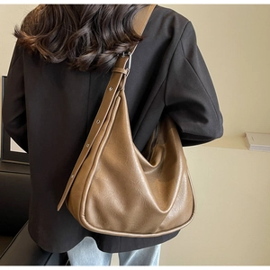Brown retro oversized leather tote bag showing a sleek crescent shape and shoulder drape
