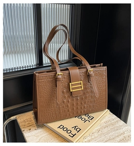 Macro view of brown crocodile texture leather and gold metal buckle on tote bag