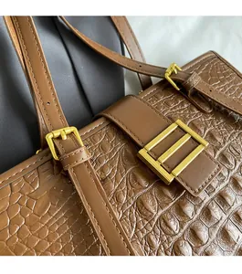 Detailed macro of brown crocodile pattern leather tote with premium gold metal hardware