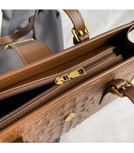 Close-up of brown crocodile texture tote bag with smooth golden zipper and magnetic closure