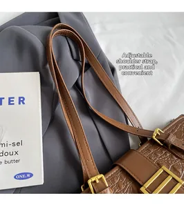 Detail of adjustable shoulder strap with golden metal buckle on brown crocodile tote bag