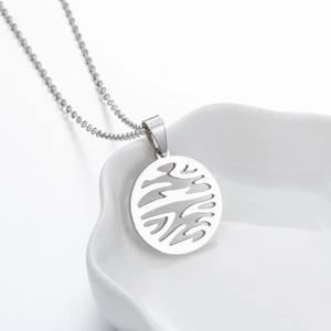 Macro shot of silver geometric hollow circular pendant necklace in a white ceramic dish