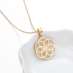 Detailed macro view of a gold circular geometric flower pendant necklace on white ceramic