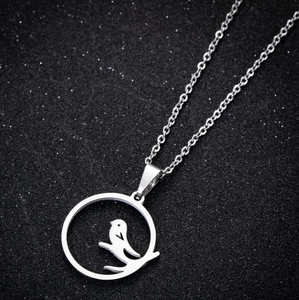 Close-up of laser-cut bird on branch pendant with stainless steel chain on black base