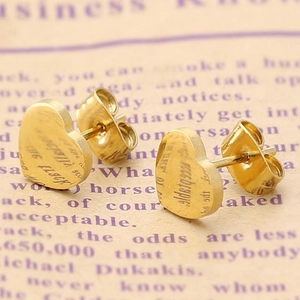 Boucles d'oreilles cœur dorées avec poli miroir présentées sur un fond de journal rétro