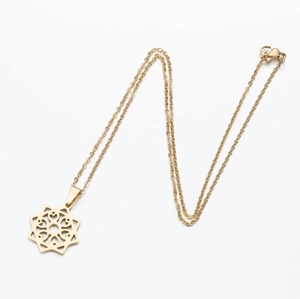 Detail of golden stainless steel necklace with laser-cut geometric mandala star pendant