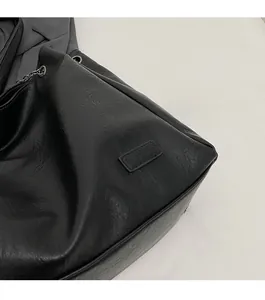Dettaglio borsa tote in pelle nera con etichetta fashion goffrata e occhiello in metallo