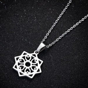 Macro shot of silver-colored hollow star-shaped pendant with heart details on black texture