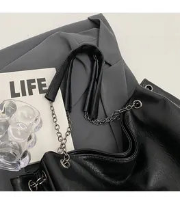 Dettaglio borsa shopper nera in pelle opaca con tracolla in catena di metallo argento