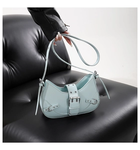 Detail of mint green crescent bag with silver buckle and rivets on leather sofa
