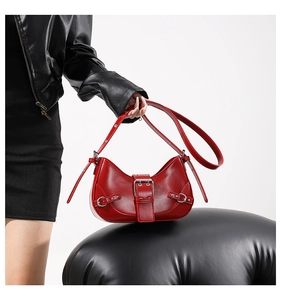 Close-up of a red crescent moon bag featuring a large silver metal buckle and Y2K style