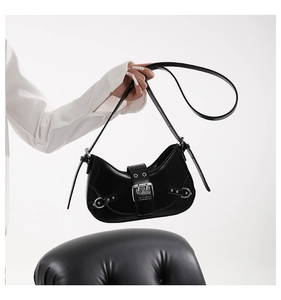 Close-up of black crescent bag featuring silver rivet buckles and polished leather texture