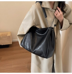 Dettaglio borsa tote in morbida pelle nera con tracolla a catena e logo fashion