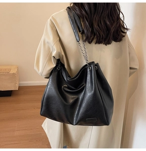 Dettaglio della borsa tote nera in pelle PU con catena d'argento e toppa decorativa