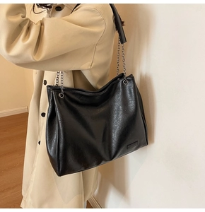 Dettaglio della borsa tote nera in ecopelle con catena argento e logo di moda