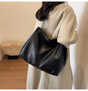 Dettaglio borsa tote nera in pelle PU con tracolla a catena e logo in rilievo