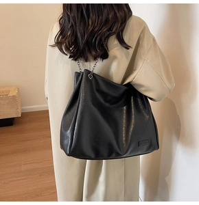 Dettaglio di borsa tote in pelle PU nera con trama litchi e tracolla a catena