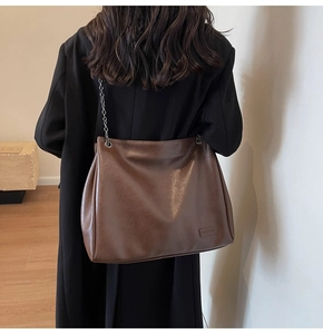 Dettaglio della borsa tote vintage marrone con tracolla a catena sulla spalla