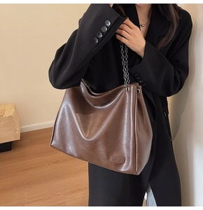 Dettaglio della borsa tote vintage marrone con catena in metallo e etichetta a rilievo