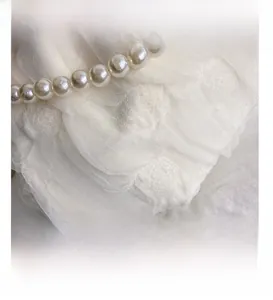 Macro view of white wavy textured fabric adorned with delicate cream pearl detail