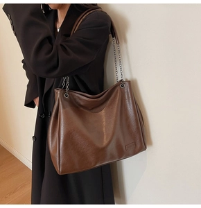 Dettaglio borsa tote marrone scuro in pelle lucida con elegante tracolla a catena argento