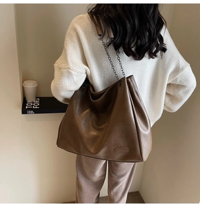 Dettaglio borsa tote in pelle marrone con logo FASHION a rilievo e tracolla a catena