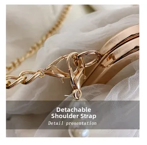 Detail of detachable gold chain strap with elegant white pearl charms on lace handbag